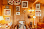 This cozy cabin interior features warm wood paneling and a unique cowhide armchair, creating a rustic yet inviting atmosphere.