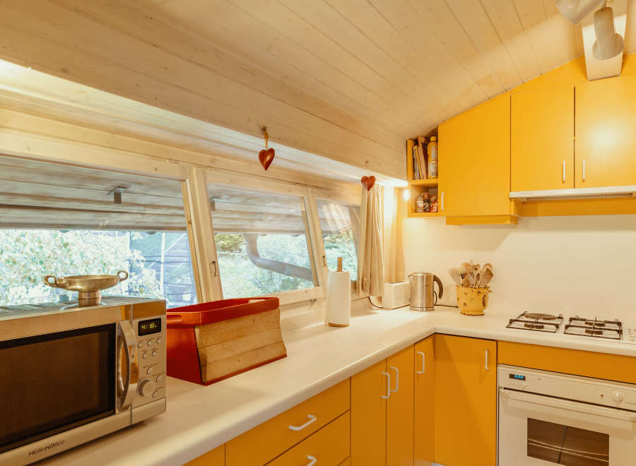This charming kitchen features a bright and inviting atmosphere with its sunny yellow cabinetry and light-colored wooden ceiling.