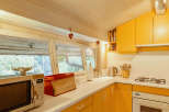 This charming kitchen features a bright and inviting atmosphere with its sunny yellow cabinetry and light-colored wooden ceiling.