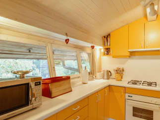 This charming kitchen features a bright and inviting atmosphere with its sunny yellow cabinetry and light-colored wooden ceiling.