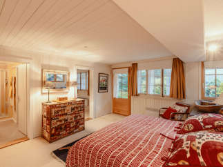 This cozy bedroom features a unique, patterned dresser and a comfortable bed with decorative pillows.