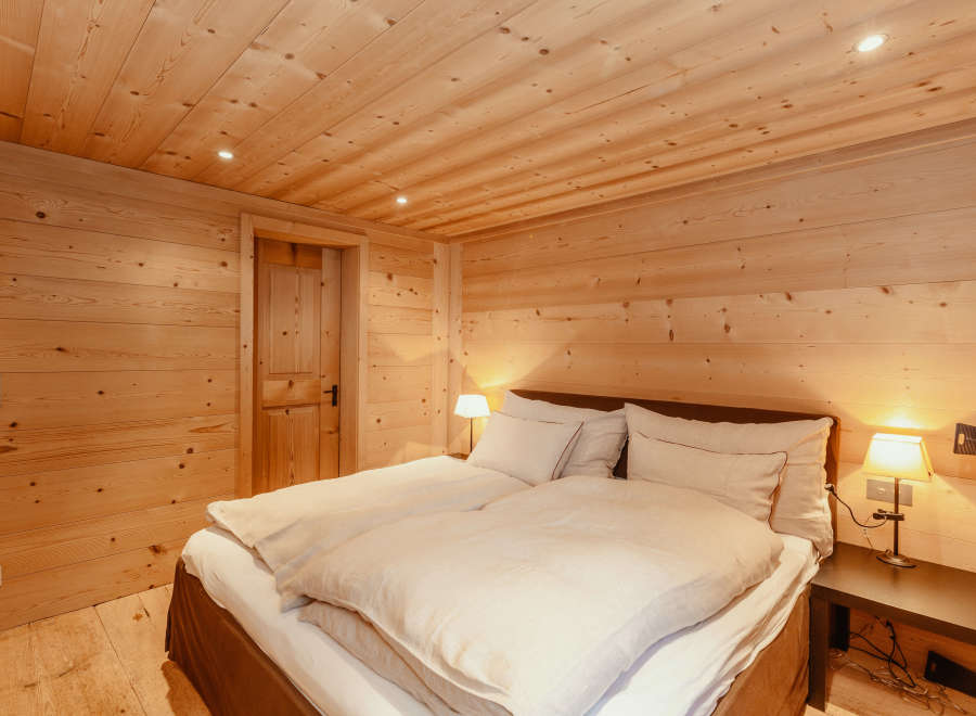 Experience the warmth of a cozy bedroom with wooden walls and ceiling.