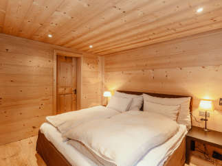 Experience the warmth of a cozy bedroom with wooden walls and ceiling.