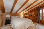 Experience the warmth of this cozy bedroom with its charming wooden accents and inviting ambiance.