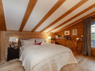 Experience the warmth of this cozy bedroom with its charming wooden accents and inviting ambiance.