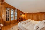 Experience the charm of this cozy bedroom, featuring warm wooden accents and a unique sloped ceiling.