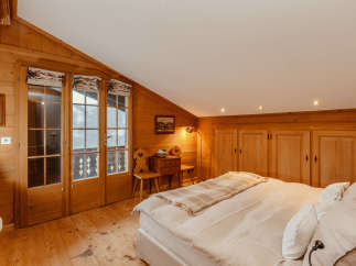 Experience the charm of this cozy bedroom, featuring warm wooden accents and a unique sloped ceiling.