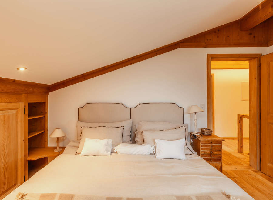 This cozy bedroom features a warm, inviting atmosphere with wooden accents and a comfortable bed.