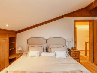This cozy bedroom features a warm, inviting atmosphere with wooden accents and a comfortable bed.