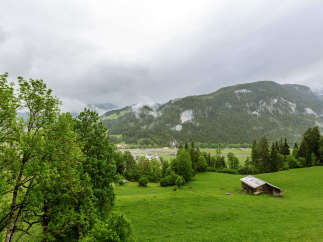Discover the tranquility of this stunning landscape, featuring lush green fields and majestic mountains.