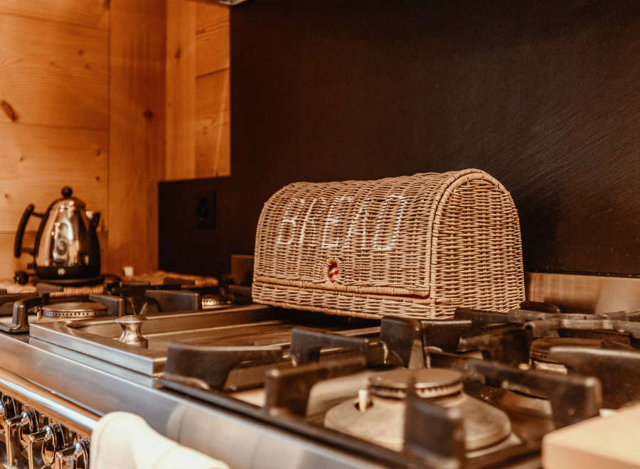 A cozy kitchen scene featuring a woven bread basket resting on a stainless steel gas stove.