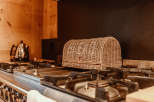 A cozy kitchen scene featuring a woven bread basket resting on a stainless steel gas stove.