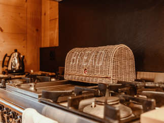 A cozy kitchen scene featuring a woven bread basket resting on a stainless steel gas stove.