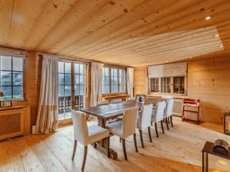 Experience the warmth of this inviting dining room, featuring a rustic wooden table and elegant white chairs.