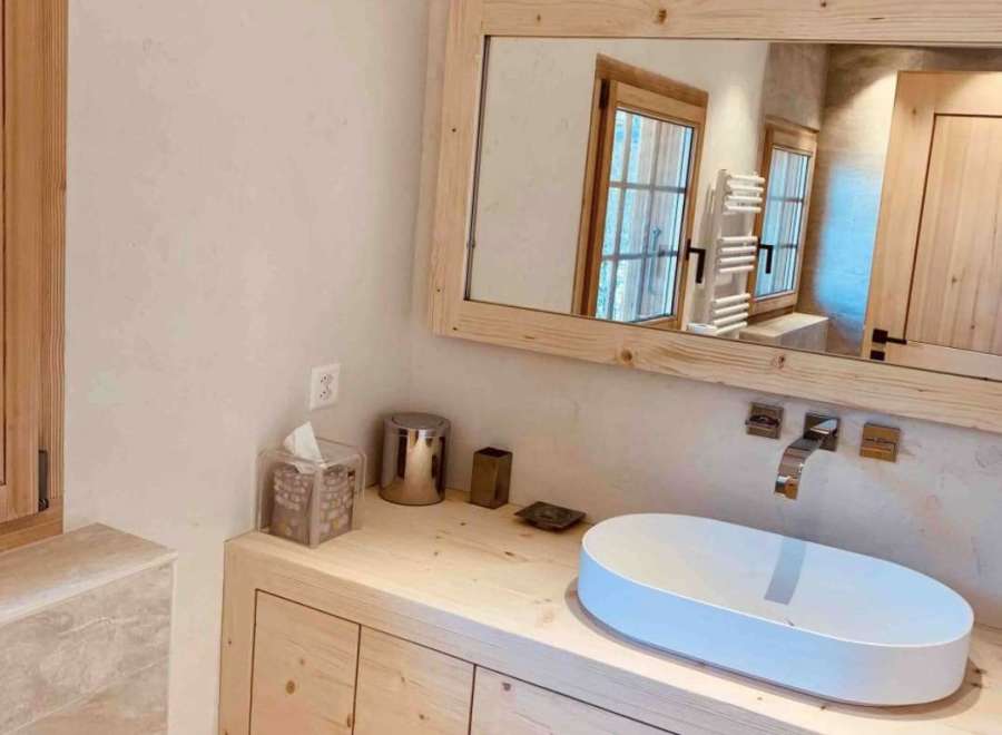 This stunning bathroom features a modern design with a natural wood vanity and a sleek, oval-shaped sink.