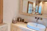 This stunning bathroom features a modern design with a natural wood vanity and a sleek, oval-shaped sink.