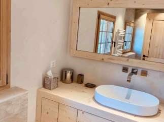 This stunning bathroom features a modern design with a natural wood vanity and a sleek, oval-shaped sink.