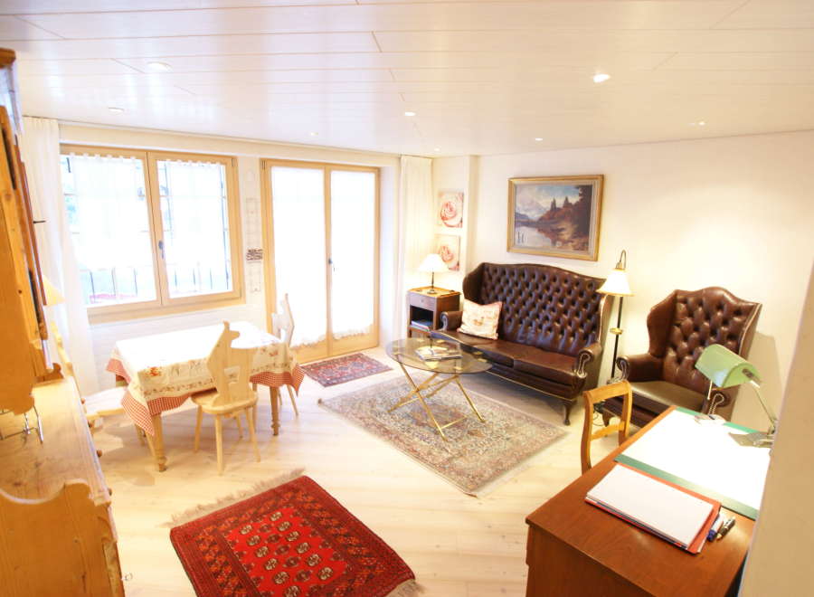 This charming living space features a cozy seating area with a tufted leather sofa and armchair, perfect for relaxation.