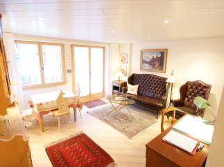 This charming living space features a cozy seating area with a tufted leather sofa and armchair, perfect for relaxation.