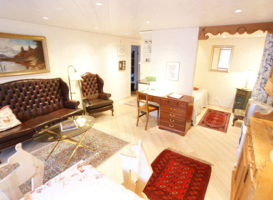 This charming living space features a classic Chesterfield sofa and a cozy armchair, perfect for relaxing.