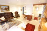This charming living space features a classic Chesterfield sofa and a cozy armchair, perfect for relaxing.