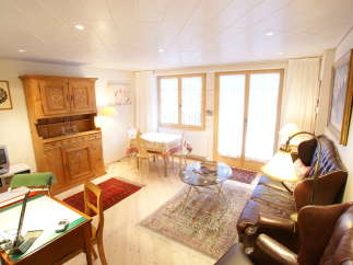 This charming living space features a cozy seating area with a leather sofa and armchairs, perfect for relaxation.