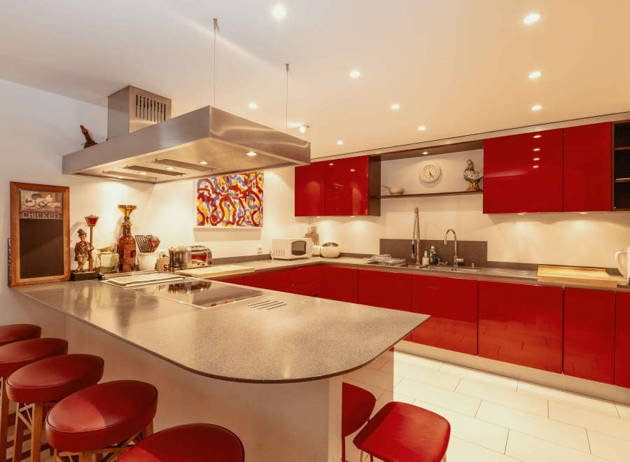 This modern kitchen boasts sleek red cabinetry and a spacious island with seating, perfect for entertaining.