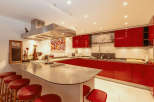This modern kitchen boasts sleek red cabinetry and a spacious island with seating, perfect for entertaining.