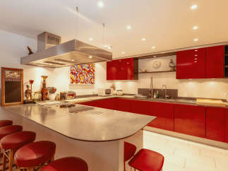 This modern kitchen boasts sleek red cabinetry and a spacious island with seating, perfect for entertaining.