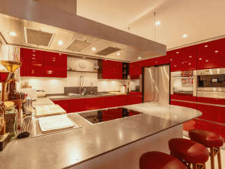 This modern kitchen boasts sleek red cabinetry and a spacious island with a cooktop, perfect for culinary enthusiasts.