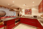 This modern kitchen boasts sleek red cabinetry and a stainless steel range hood, creating a stylish and functional space.