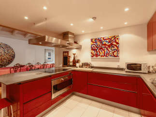 This modern kitchen boasts sleek red cabinetry and a stainless steel range hood, creating a stylish and functional space.