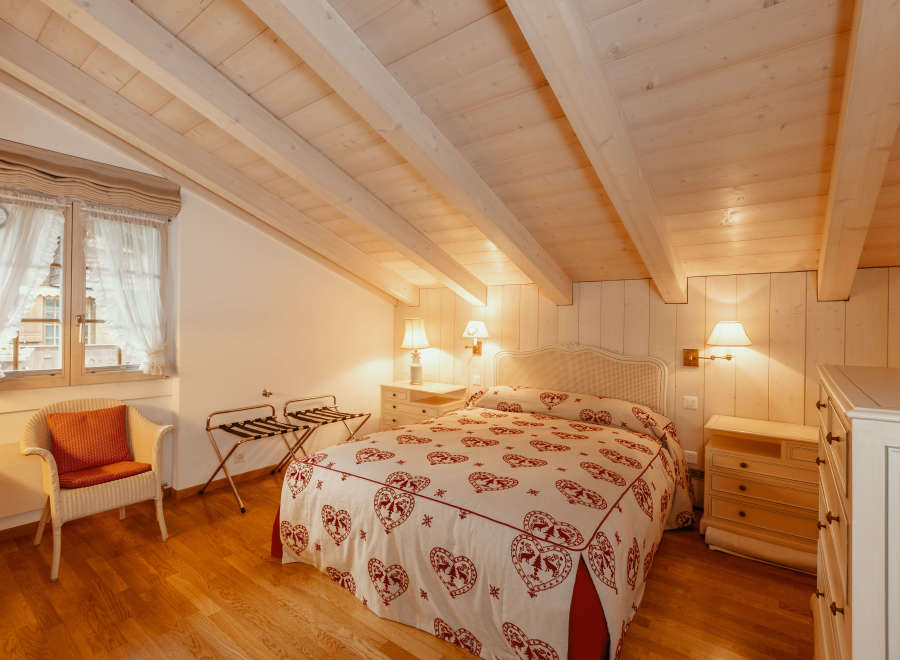 This charming bedroom features a cozy ambiance with its wooden ceiling and walls.