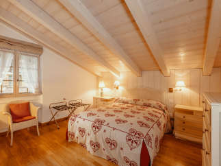 This charming bedroom features a cozy ambiance with its wooden ceiling and walls.
