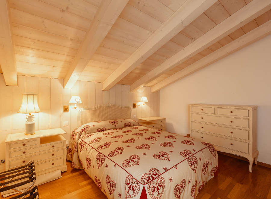 This cozy bedroom features a charming wooden ceiling and walls, creating a warm and inviting atmosphere.