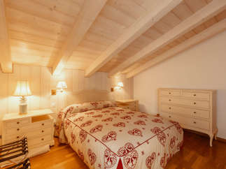 This cozy bedroom features a charming wooden ceiling and walls, creating a warm and inviting atmosphere.