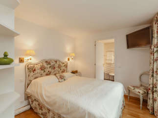 This charming bedroom features a cozy bed with a floral headboard and matching accents, creating a warm and inviting atmosphere.