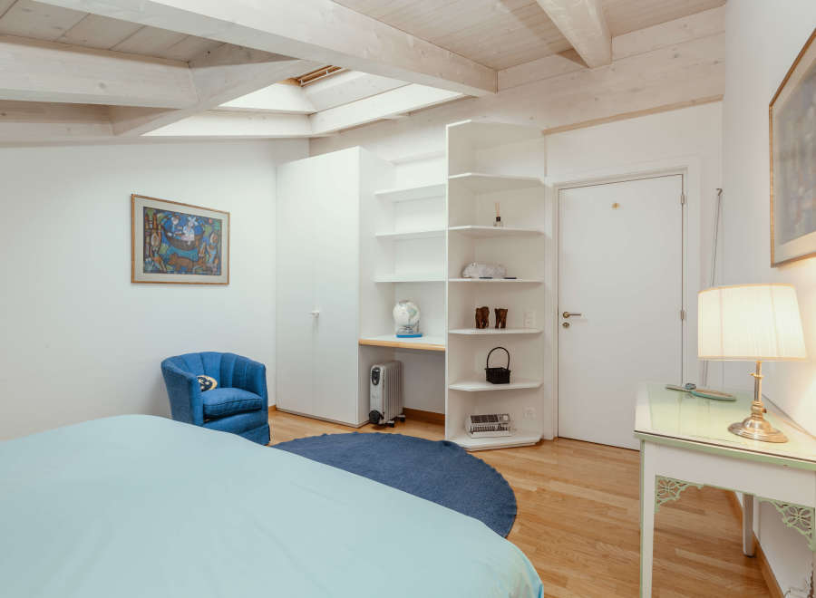 This charming bedroom features a cozy blue armchair and a comfortable bed.