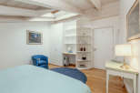 This charming bedroom features a cozy blue armchair and a comfortable bed.