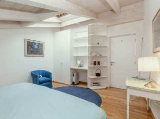 This charming bedroom features a cozy blue armchair and a comfortable bed.