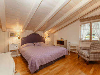 This charming bedroom features a cozy ambiance with its wooden ceiling and warm lighting.