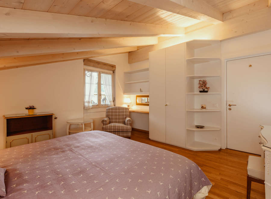 This charming bedroom features a cozy atmosphere with a wooden ceiling and beams.
