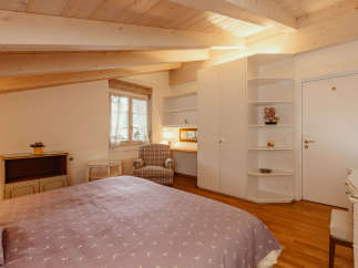 This charming bedroom features a cozy atmosphere with a wooden ceiling and beams.