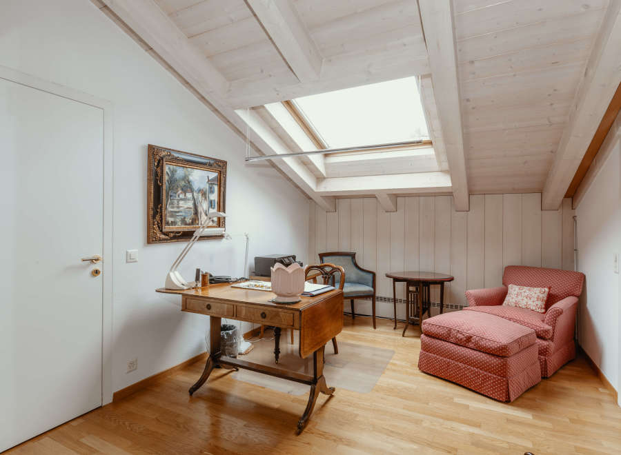 This charming room features a unique sloped ceiling with exposed wooden beams, creating a cozy and inviting atmosphere.