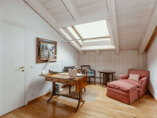 This charming room features a unique sloped ceiling with exposed wooden beams, creating a cozy and inviting atmosphere.