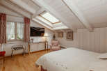 This charming bedroom features a unique sloped ceiling with exposed wooden beams, creating a cozy and inviting atmosphere.