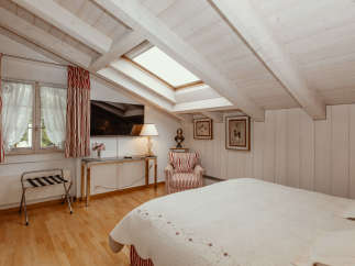 This charming bedroom features a unique sloped ceiling with exposed wooden beams, creating a cozy and inviting atmosphere.