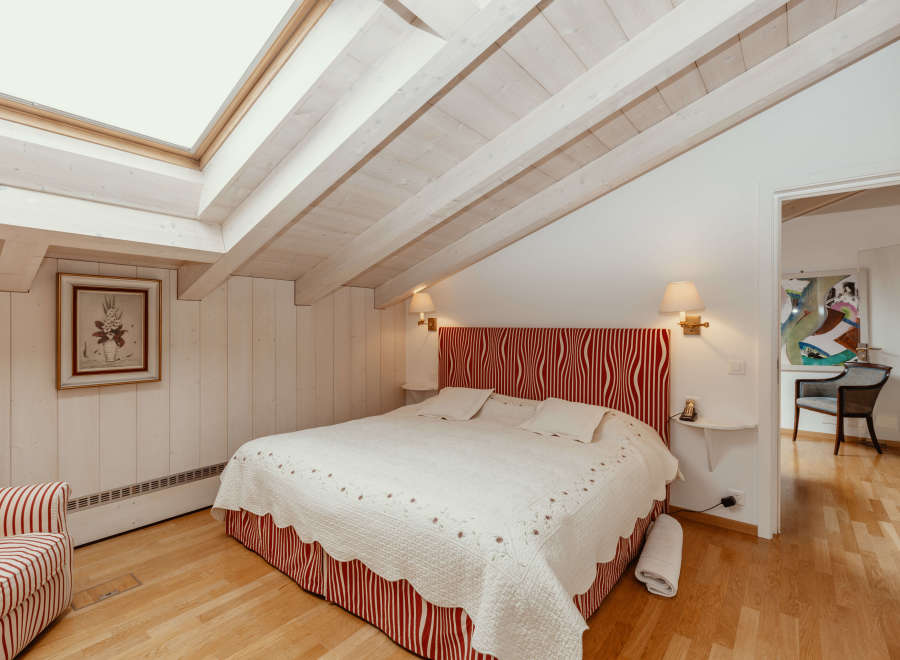 This charming bedroom features a unique sloped ceiling with exposed wooden beams, creating a cozy and inviting atmosphere.