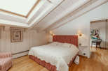 This charming bedroom features a unique sloped ceiling with exposed wooden beams, creating a cozy and inviting atmosphere.