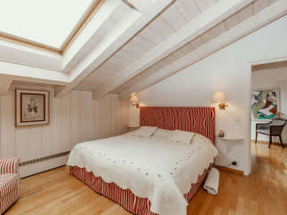 This charming bedroom features a unique sloped ceiling with exposed wooden beams, creating a cozy and inviting atmosphere.
